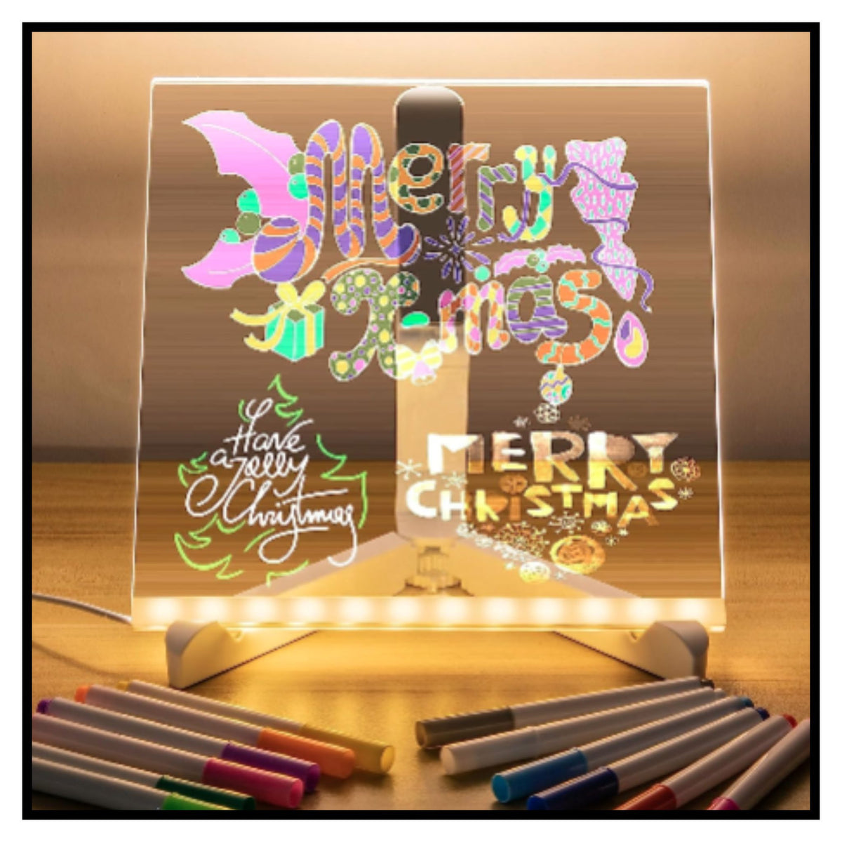 Glowing acrylic LED light box on wooden surface displaying colorful Christmas-themed lettering and designs including Merry Christmas