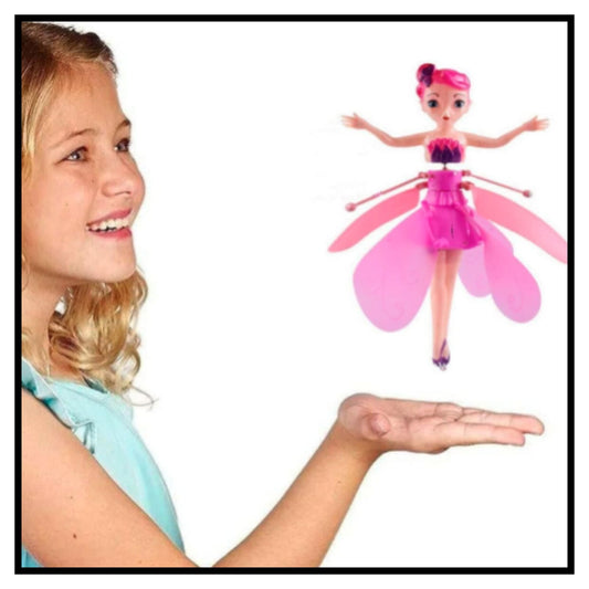 Young girl smiling and holding out her hand toward a floating pink fairy doll with wings and arms shown against plain white background