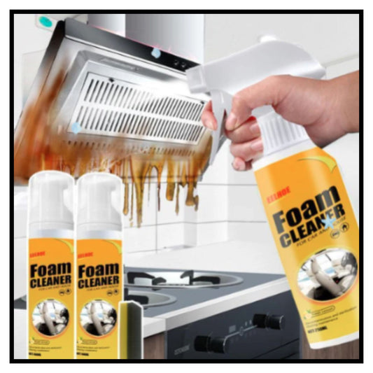 A hand holding a spray bottle of foam cleaner in front of a kitchen range hood with burnt residue with two cans of foam cleaner shown in the foreground