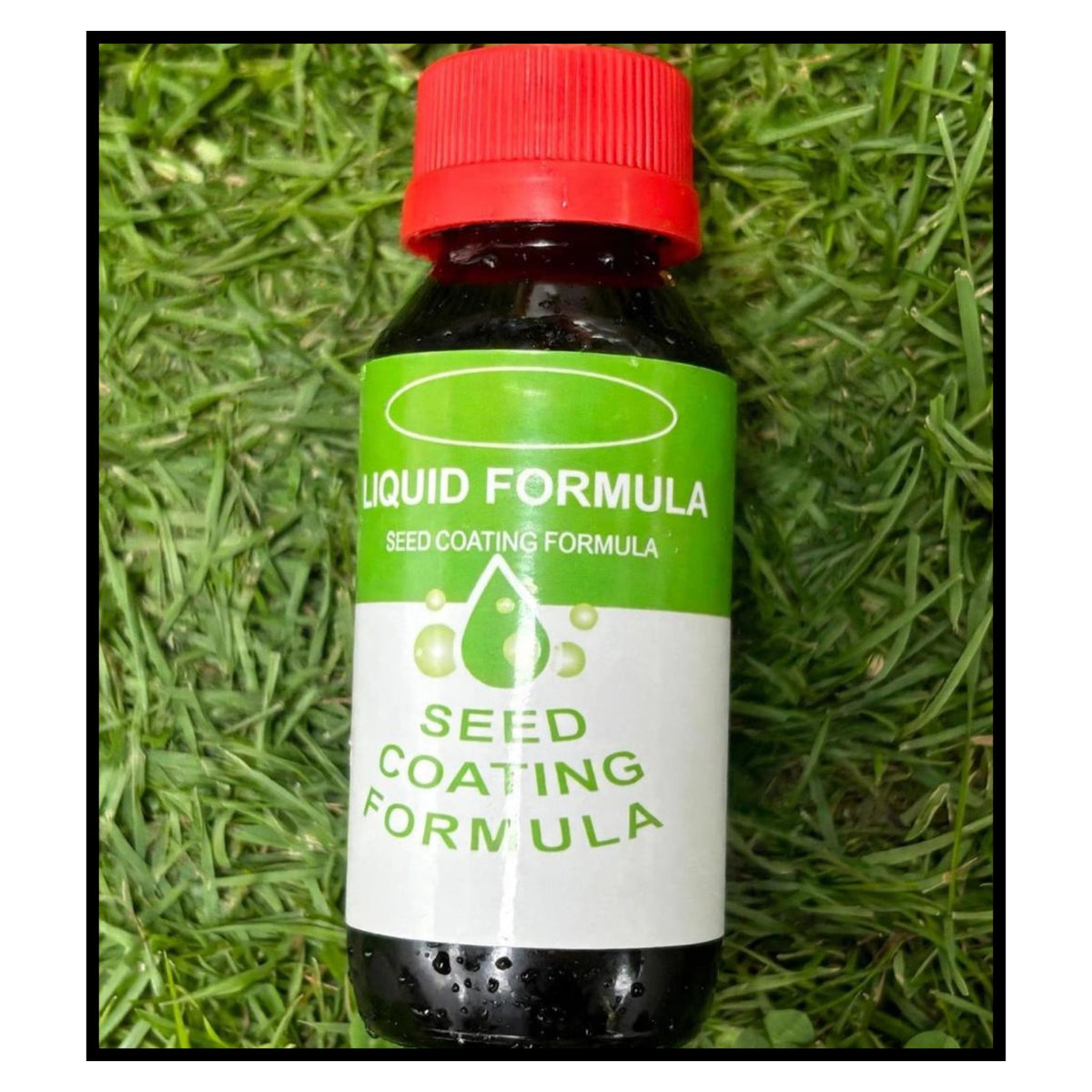 Small bottle of seed coating liquid formula with green and white label and red cap placed on grass background
