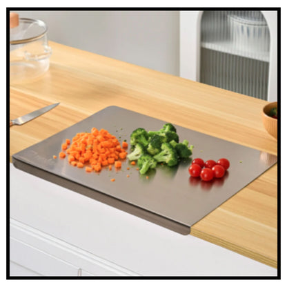 Stainless steel chopping board on kitchen countertop with chopped carrots broccoli and cherry tomatoes