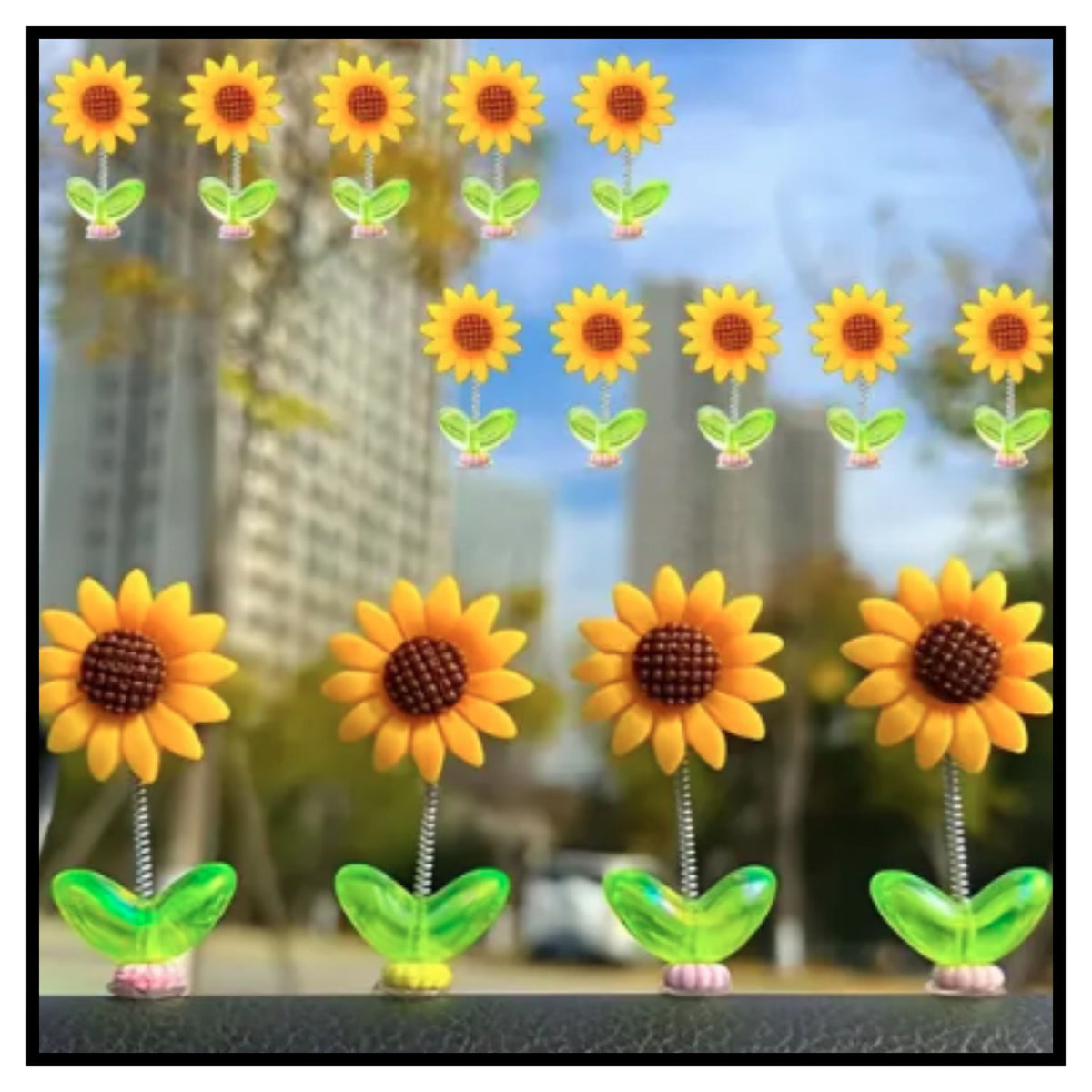 Four yellow shaking head sunflower dancing ornaments with green leaves on car dashboard with blurred outdoor background