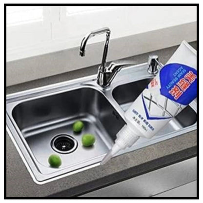 Tiles gap filler tube applying white filler to kitchen sink gap near stainless steel faucet with lime fruits in sink