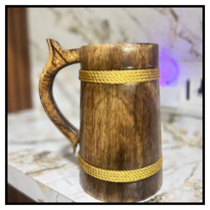 Wooden beer stein mug with carved handle and two braided rope bands on marble patterned surface